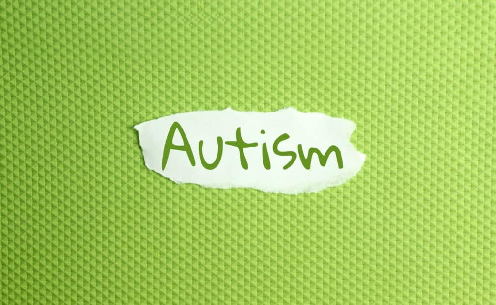a torn paper written with inscription autism on a green background
