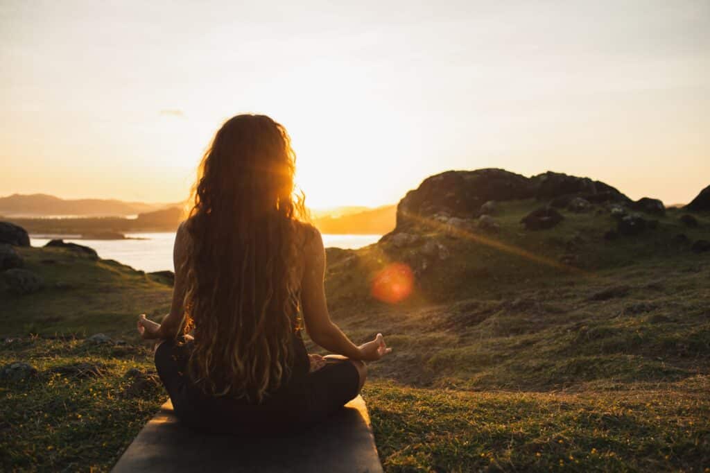 Femme méditant le yoga seule au lever du soleil dans les montagnes. Vue de derrière. Voyage Mode de vie Esprit