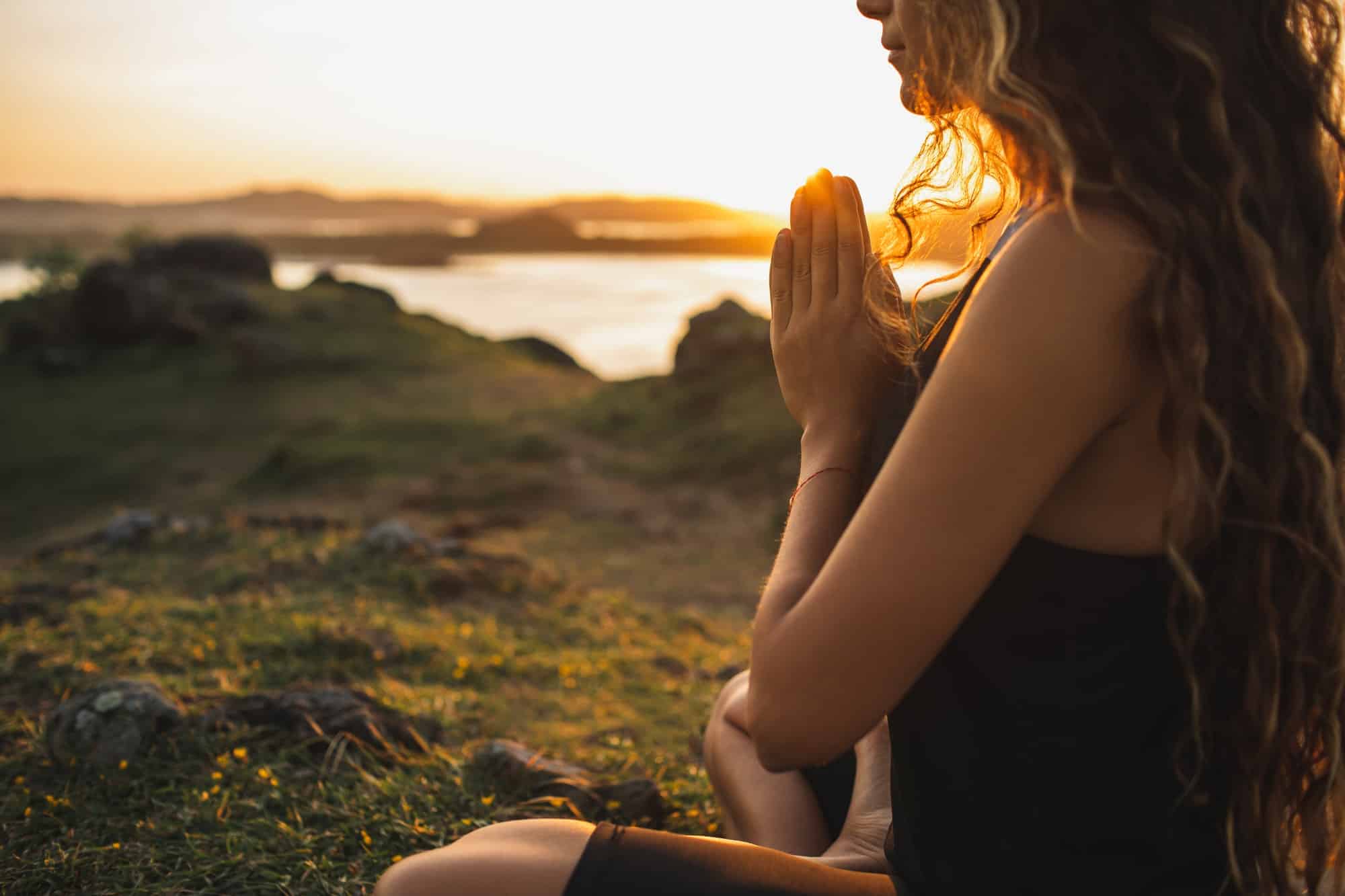 Femme priant seule au lever du soleil. Fond naturel. Concept spirituel et émotionnel